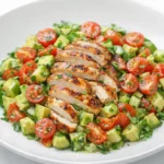 Healthy avocado chicken salad with grilled chicken, cherry tomatoes, and diced avocado in a white bowl