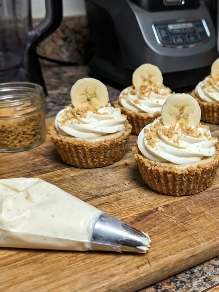 No-bake Mini Banana Cream Pies topped with whipped cream and banana slices on wooden board