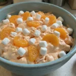 Orange Creamsicle Fluff Salad topped with mandarin oranges and mini marshmallows in a blue bowl