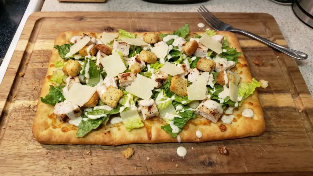 Chicken Caesar Flatbread topped with grilled chicken, romaine, Parmesan, croutons, and creamy dressing on crispy crust