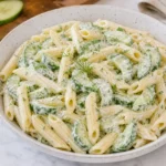 Fresh cucumber pasta salad with penne, sliced cucumbers, and creamy dill dressing in a white bowl