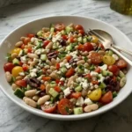 Mediterranean White Bean Salad with feta, tomatoes, cucumber, and olives in a white bowl