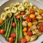 Pesto Chicken Tortellini and Veggies with asparagus, cherry tomatoes, and basil pesto in a bowl
