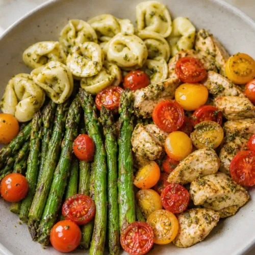 Pesto Chicken Tortellini and Veggies with asparagus, cherry tomatoes, and basil pesto in a bowl