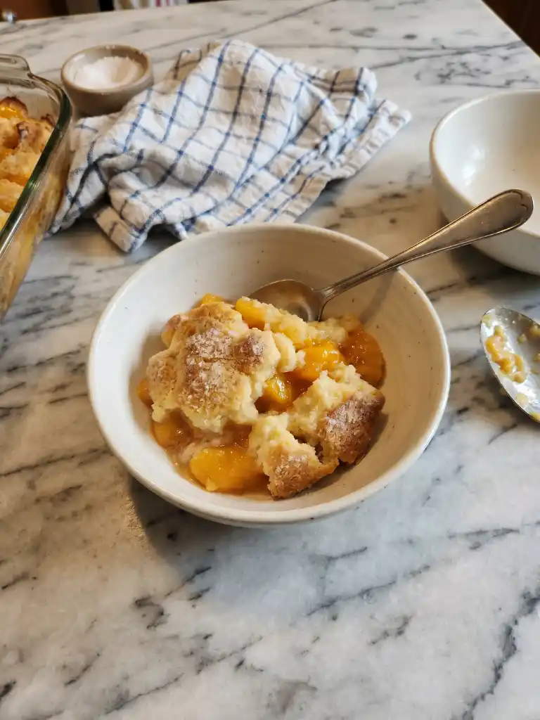 Southern peach cobbler served in a bowl with golden crust and juicy peach filling